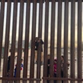 From the U.S. side of the border, children on the Mexican side are seen playfully climbing the fence.