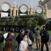 Visitors walk past Chinese military vehicles carrying ballistic missiles.