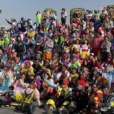 Hundreds of colorful clowns pose on stairs for a group photo