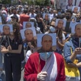Angry demonstrators carry pictures of Nizar Banat in the West Bank.