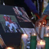 A person places a candle near a memorial for Donovon Lynch during a vigil.