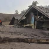 Villagers inspect the damage as houses are seen buried in volcanic ash in Indonesia.