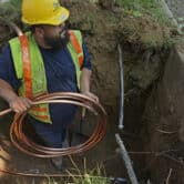 A worker prepares to install a new copper water service line.