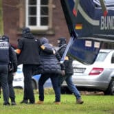 A suspect is escorted from a police helicopter by police officers in Germany.