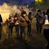 Protesters run after clashing with riot police in Peru.