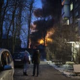 Residents watch a fire caused by a drone strike in Kyiv.
