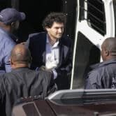 Sam Bankman-Fried is led out of a van while handcuffed in the Bahamas.