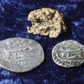 A gold nugget and 17th-century silver coins with Arabic inscriptions.