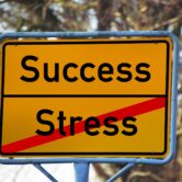 Yellow sign with the word success on top and the word stress struck through