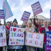 Trans rights protesters hold signs as they demonstrate outside the Scottish Parliament.
