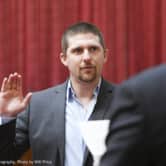 Derrick Evans raises his hand during a swearing-in ceremony in West Virginia.