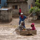 A man steers a boat carrying two children on a flooded street in Madagascar.