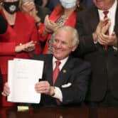 Henry McMaster holds up a bill he just signed during a ceremony in South Carolina.