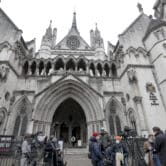 Media members stand outside the High Court in London.