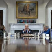 Joe Biden, Kamala Harris and three Democratic lawmakers talk while sitting at a table in the White House's Roosevelt Room.