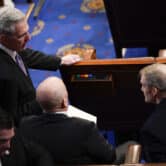 Kevin McCarthy speaks with two other lawmakers in the U.S. House chamber.