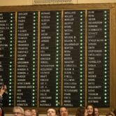 A board listing the names of Minnesota House of Representatives members