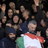 People, surrounded by mourners, carry a corpse covered in a Palestinian flag during a funeral in the West Bank.