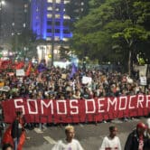 Demonstrators in Brazil march while holding a banner that reads in Portuguese "We are Democracy."
