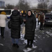 Ukrainians wait on a street blocked off after a rocket attack in Kyiv.