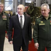 Valery Gerasimov, Vladimir Putin and Sergei Shoigu walk in a building in Moscow.