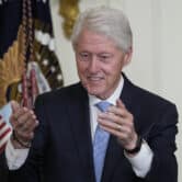 Bill Clinton blows a kiss to someone during an event in the East Room of the White House.