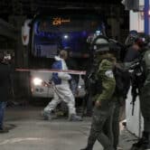 Israeli police examine the scene of a border crossing stabbing in front of a bus.