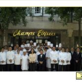 a group photo shows chefs and waiters outside restaurant with a sign written in cursive that says Champs Elysees