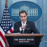 John Kirby points while standing in front of the American flag during a press briefing at the White House.