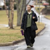 A teenage girl carries a reusable bottle as she walks down a wet street.