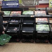 A customer checks nearly empty fruit and vegetable shelves at a London supermarket.