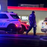 An officer carrying a rifle walks by police vehicles in front of a Burger King restaurant.
