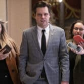 Matt Gaetz speaks to reporters holding out their phones while walking on Capitol Hill.