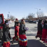 A child holds a sign that reads "MISSING & MURDERED INDIGENOUS WOMEN" as people walk during a march in South Dakota.