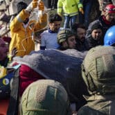 People carry a woman on a stretcher after rescuing her from a collapsed building in Turkey.