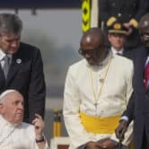 A man pushes Pope Francis in a wheelchair as he speaks to Salva Kiir at an airport in South Sudan.