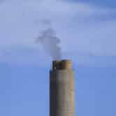 A smokestack at a coal plant emits black smoke.