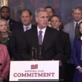Speaker McCarthy at a podium surrounded by crowd