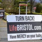 A pair of anti-abortion signs are displayed on a sidewalk.