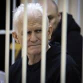 Belarusian human rights activist Ales Bialiatski sits in a defendants' cage in a Minsk courtroom.