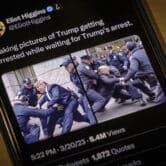 A tweet showing AI-generated images of Donald Trump getting arrested by police officers is displayed on a smartphone.