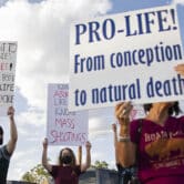 Competing anti-abortion and abortion-rights advocates hold up signs during a rally.
