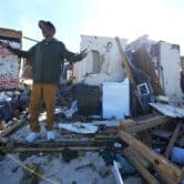 A man gestures while talking near the remains of his home, which was destroyed by a tornado.
