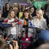 More than a dozen women stand behind Justyna Wydrzyńska as she speaks to reporters.