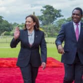 Kamala Harris waves as she walks with Hakainde Hichilema in Zambia.