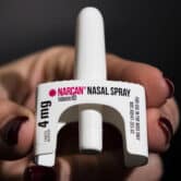 A person holds a canister of Narcan.