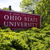 A sign for Ohio State University stands behind some bushes.