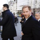 People take photos of Prince Harry as he walks in London.
