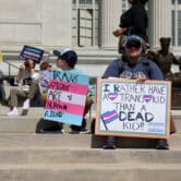 Protesters hold signs in support of transgender care for minors at the Missouri capitol.