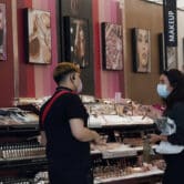 A worker wearing a face mask talks to a customer, who is also wearing a face mask, in a cosmetics shop.